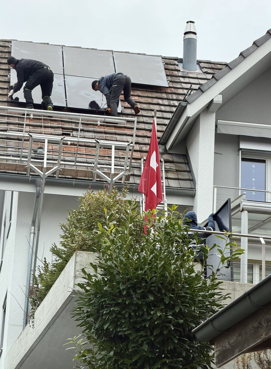 Zwei Monteure verlegen Solarmodule auf einem Ziegeldach